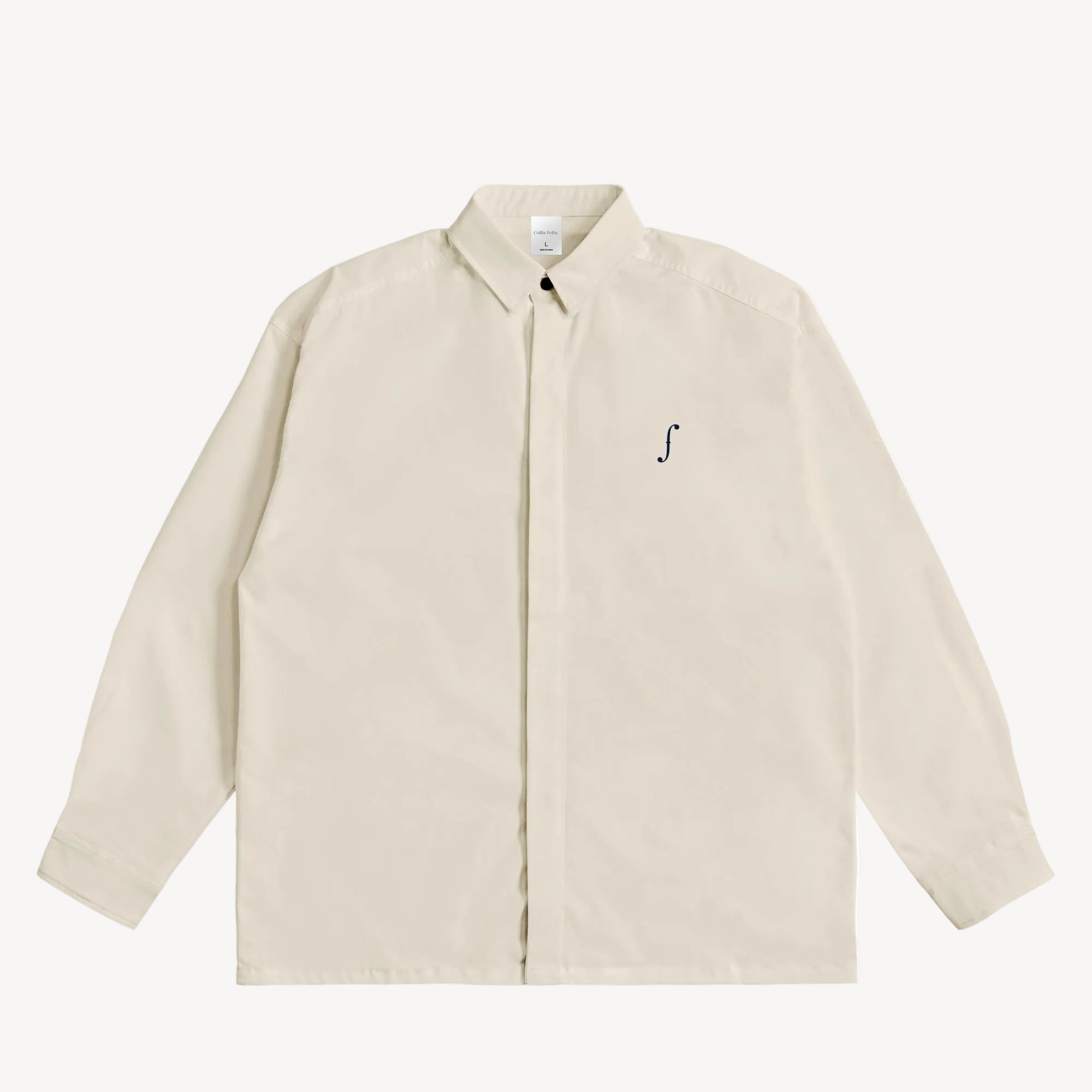Collis Felixのアイボリーのロングスリーブシャツを正面から撮影した商品画像。左胸にネイビーのブランドロゴが入っている。
