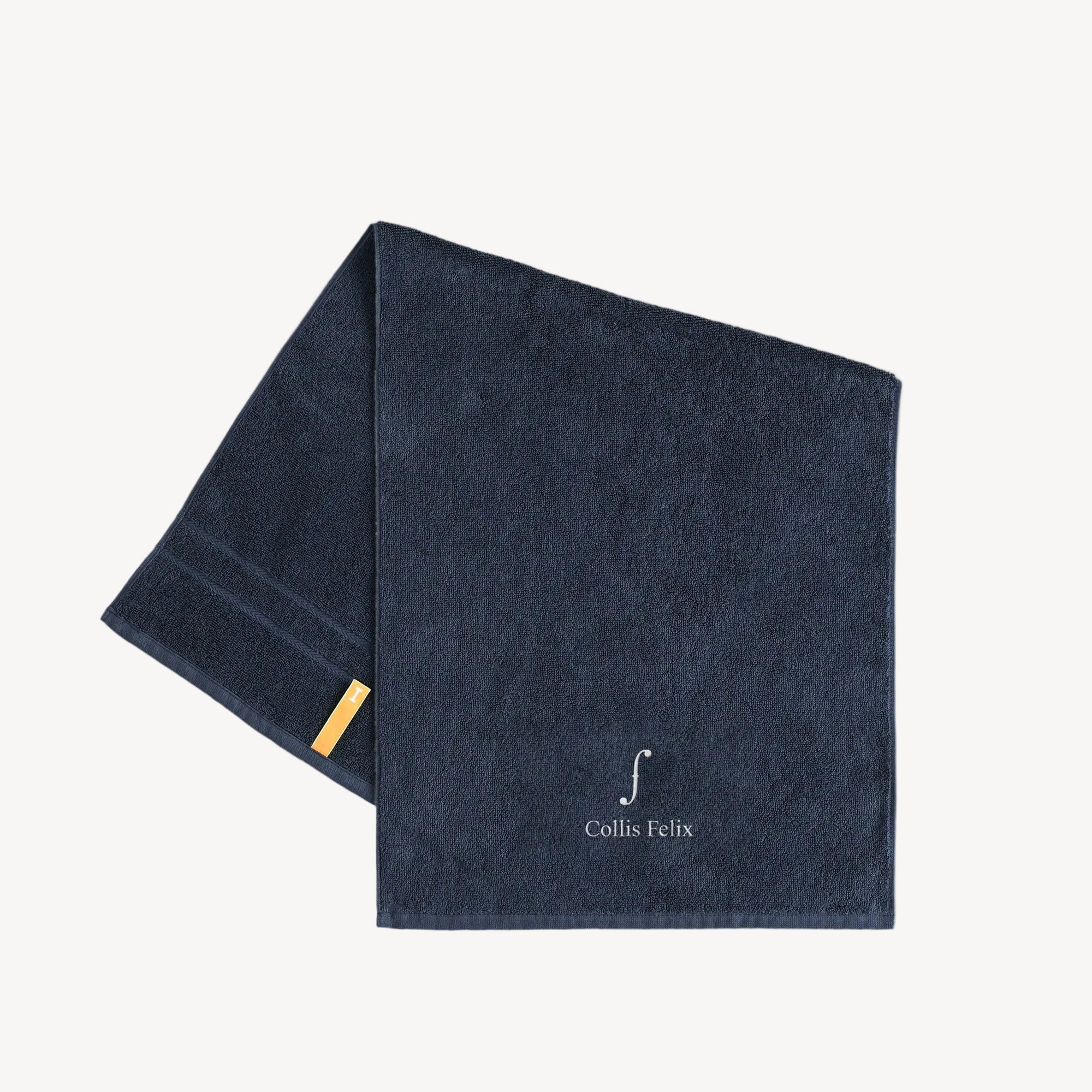 Collis Felixのネイビーのタオル。下部にブランドロゴが入り、左側にイエローのタグが付いている。