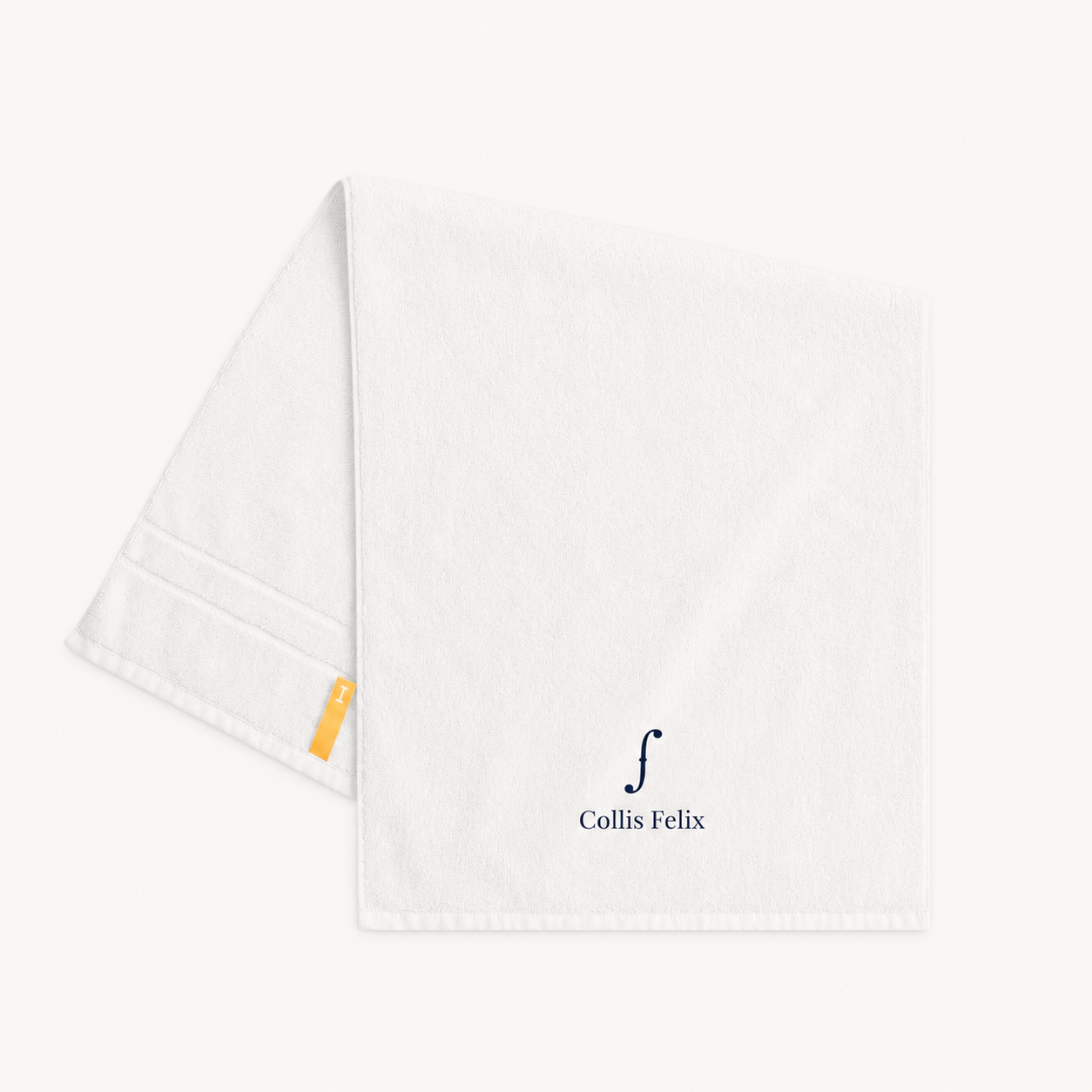 Collis Felixのホワイトのタオル。下部にブランドロゴが入り、左側にイエローのタグが付いている。